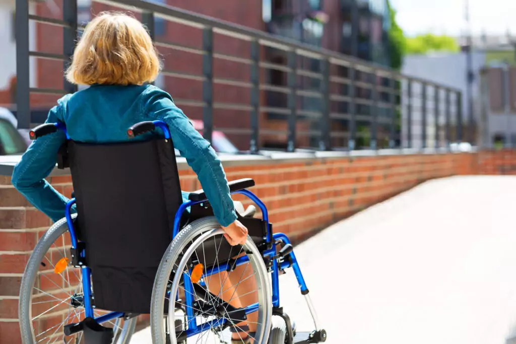 Woman uses a wheelchair on a ramp outside of a business.